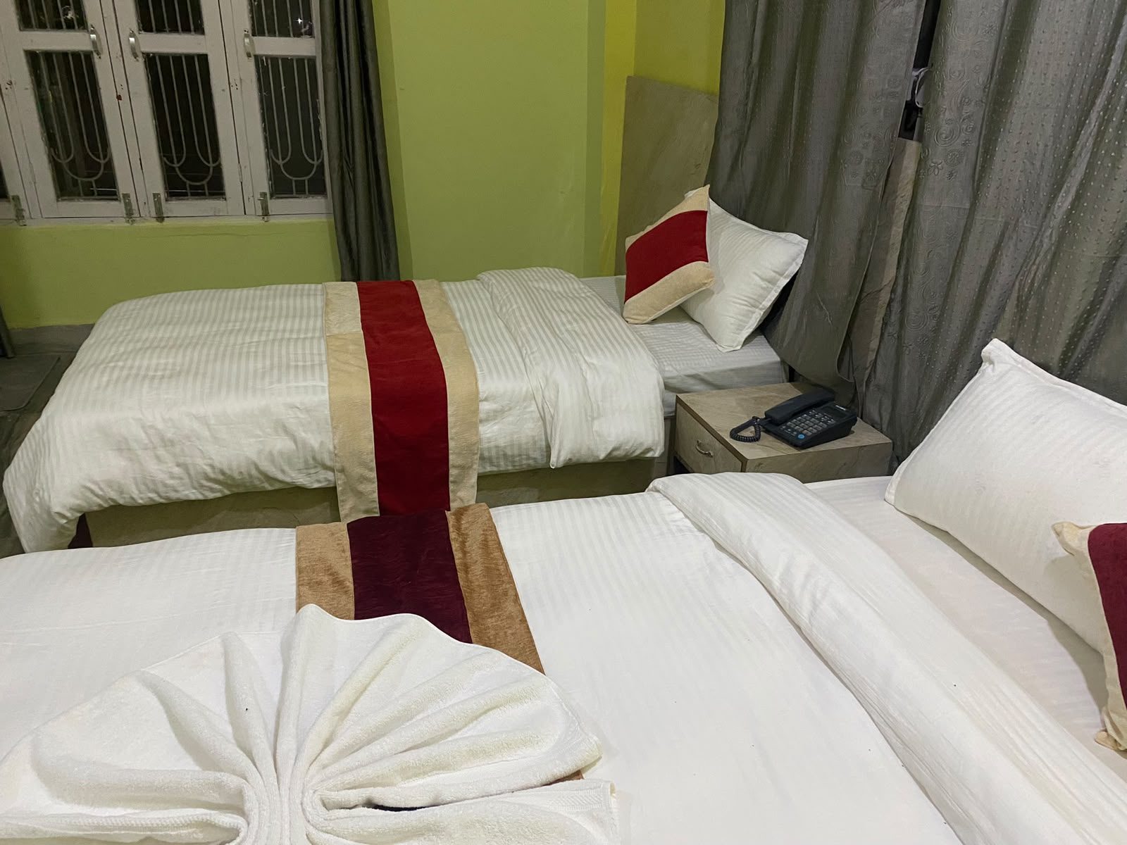 Turned-down bed with towels and drinking water at Hotel Kavya Inn